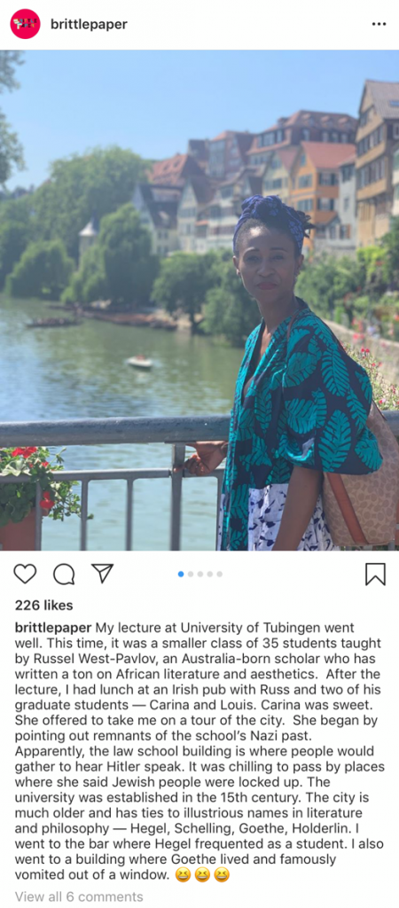 This Instagram post from Brittle Paper depicts Professor Ainehi Edoro standing in front of a river. The caption reads "My lecture at University of Tubingen went well. This time, it was a smaller class of 35 students taught by Russel West-Pavlov, an Australia-born scholar who has written a ton on African literature and aesthetics. After the lecture, I had lunch at an Irish pub with Russ and two of his graduate students — Carina and Louis. Carina was sweet. She offered to take me on a tour of the city. She began by pointing out remnants of the school’s Nazi past. Apparently, the law school building is where people would gather to hear Hitler speak. It was chilling to pass by places where she said Jewish people were locked up. The university was established in the 15th century. The city is much older and has ties to illustrious names in literature and philosophy — Hegel, Schelling, Goethe, Holderlin. I went to the bar where Hegel frequented as a student. I also went to a building where Goethe lived and famously vomited out of a window. 😆😆😆"
